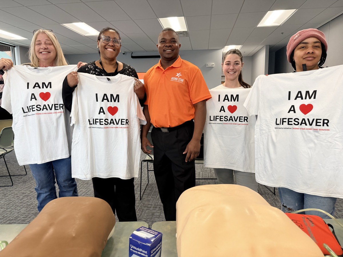 Participants holding I Am A Lifesaver shirts at a Rising Star 1,000 Hearts CPR training in Maryland